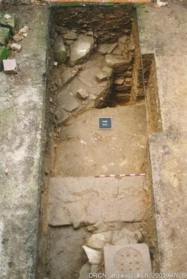 Sondagem 41, vendo-se o muro medieval e, ao fundo, o alicerce do claustro do século XVI e conduta...