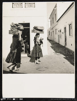 Duas mulheres na rua Sub vila com costais à cabeça