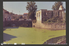 Paisagem urbana. Ponte sobre o rio, veículos e casario