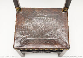 Cadeira de costas baixas em couro lavrado e com pregaria amarela